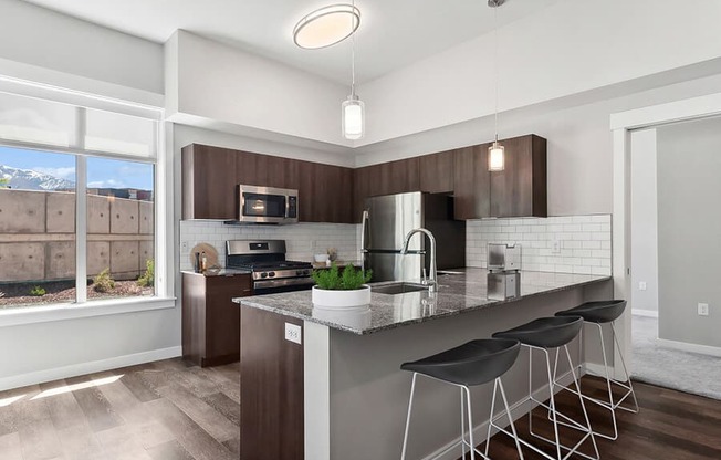Model Kitchen with Wood-Style Flooring & Dark Oak Cabinets at Seven Skies Apartments located in Sandy, UT.