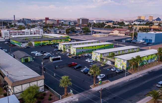 Aerial view of three two-story Fusion Las Vegas apartment in large parking lot filled with cars and Las Vegas skyline in background