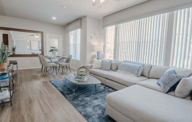 A living room with a white sofa, a coffee table, and a dining table with chairs.