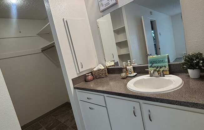 A bathroom with a sink, mirror, and cabinets.