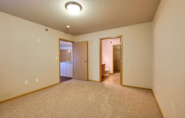 a bedroom with a door to a bathroom. Fargo, ND East Bridge Apartments