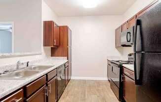 A kitchen with a black refrigerator, brown cabinets, and a white countertop.