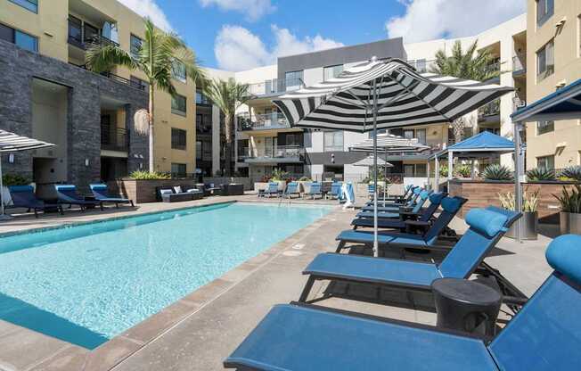 A swimming pool surrounded by blue lounge chairs and umbrellas.