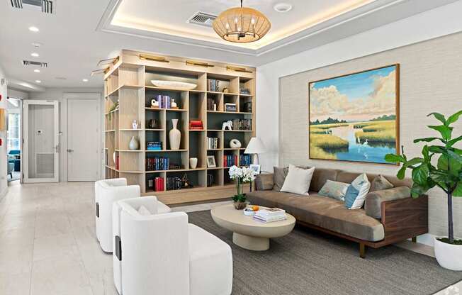 A living room with a bookshelf, a couch, and a painting on the wall.