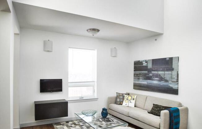 Living Room with beige couch, glass coffee table and neutral patterned rug