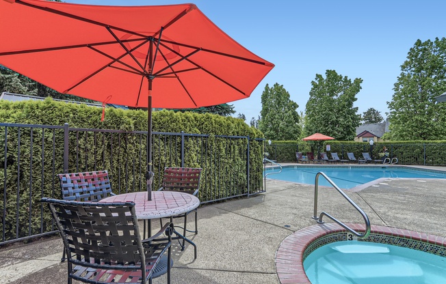 a patio with an umbrella and chairs next to a pool