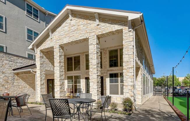 a patio with tables and chairs in front of a building