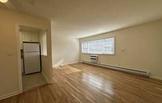 A room with wooden floors and a window with blinds.