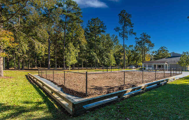 A baseball field with a fence and trees in the background.