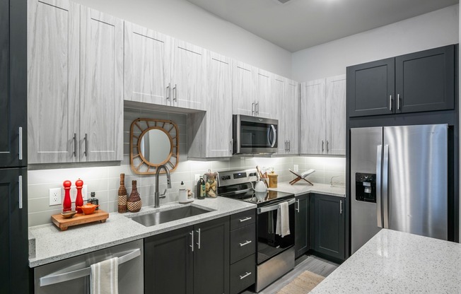 Elevate your culinary skills in our modern kitchen, featuring quartz countertops, shaker white cabinets with satin pool, and stainless steel appliances.