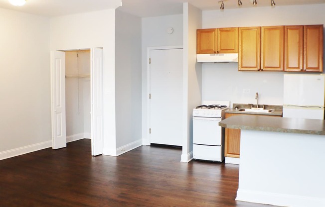 an empty kitchen with white appliances and wooden cabinets