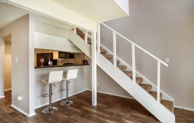 a bar under the stairs in a home with wood floors