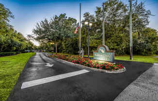 the welcome sign at the end of a road with flowers