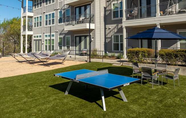 a ping pong table and chairs in front of an apartment building