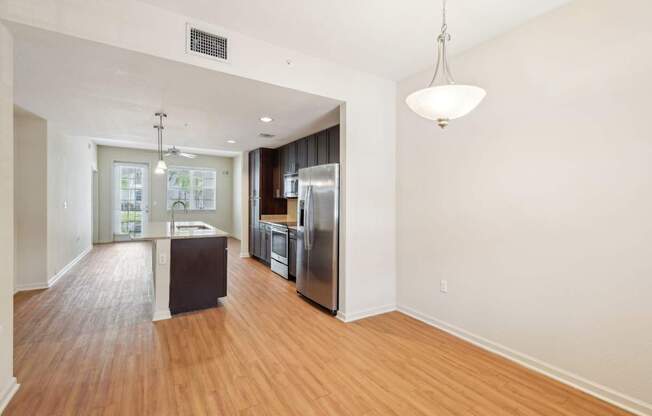 A kitchen with a refrigerator, sink, and wooden floors.