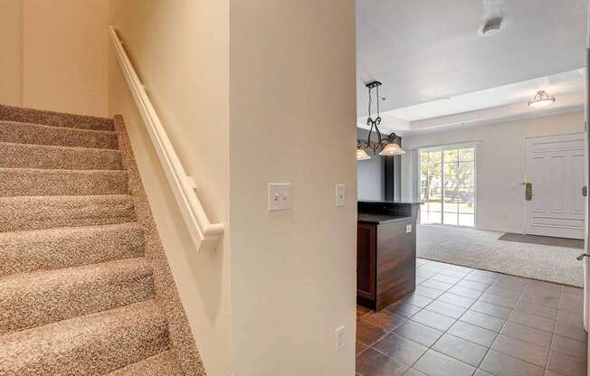 A staircase with a carpeted runner leads up to a white wall with a switch plate.