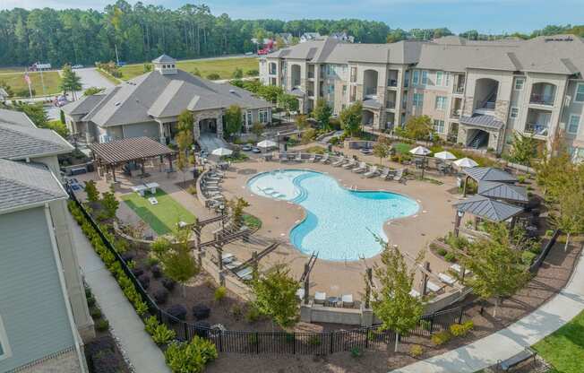 an aerial view of a swimming pool and patio area with apartment buildings