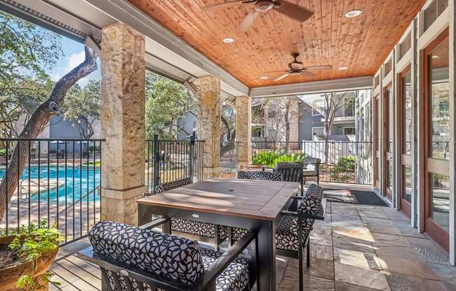 A patio with a table and chairs overlooking a pool.