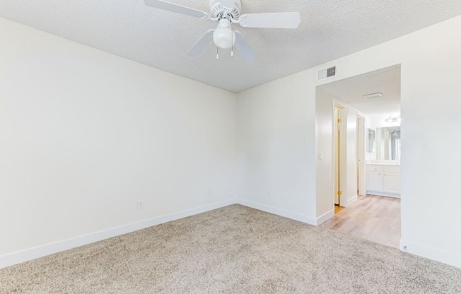 a bedroom with white walls and a ceiling fan  at Redlands Park Apts, Redlands, CA
