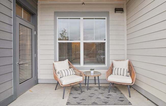 a front porch with two chairs and a small table