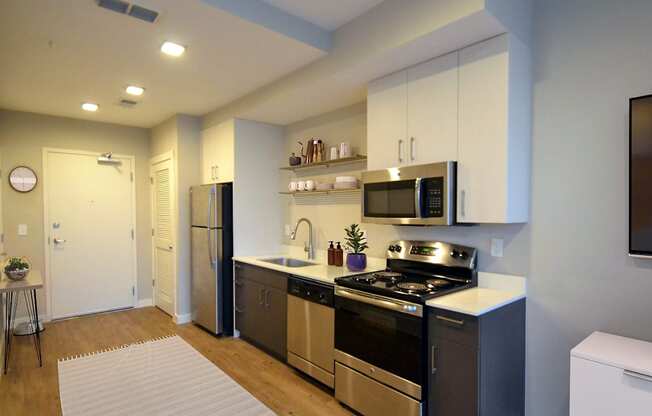 a kitchen with white cabinets and stainless steel appliances at Link Apartments® Canvas, Atlanta