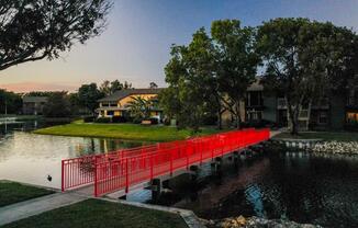 a red bridge over a lake in front of a building