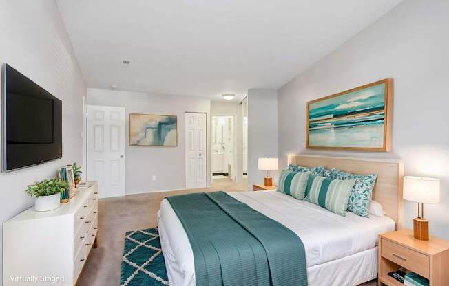 A bedroom with a bed, nightstand, and a painting on the wall.