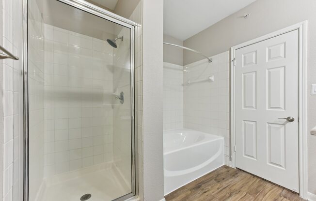 A white bathroom with a glass shower stall and a white door.