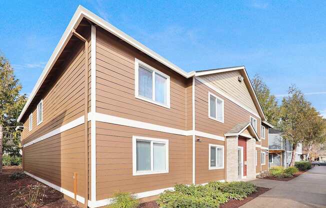 A brown house with a red door and white trim.