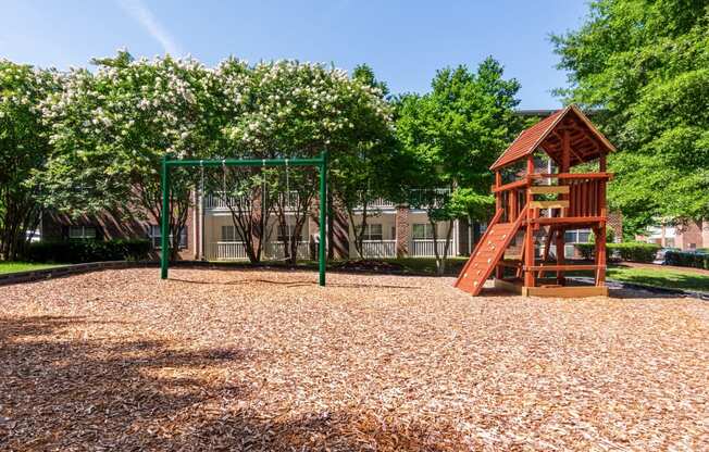 a playground with a swing set and a tree house