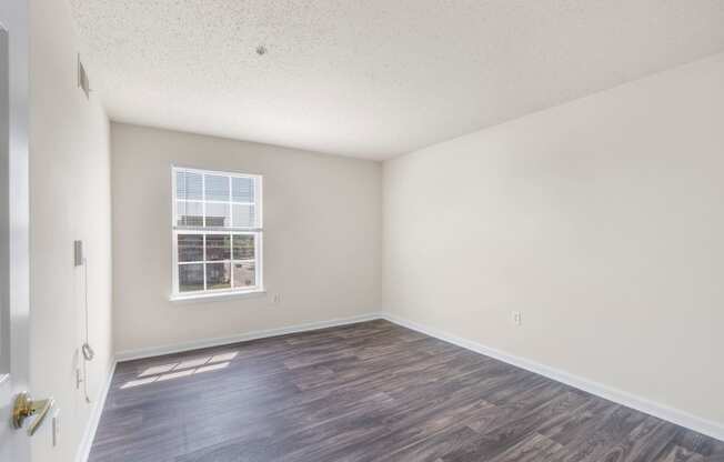 an empty living room with a window and wood flooring