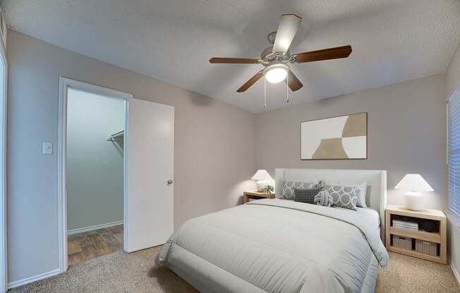 A bedroom with a bed, two lamps, and a ceiling fan.