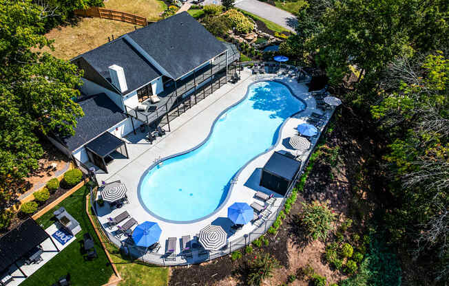 A large swimming pool surrounded by trees and a house.