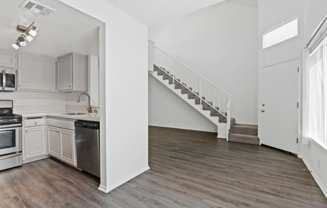 an empty kitchen and living room with white walls and wood flooring