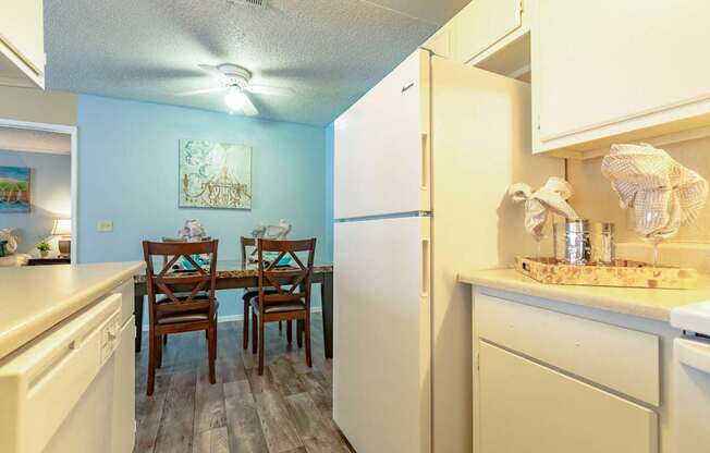 A kitchen with a white refrigerator, two chairs, and a table.