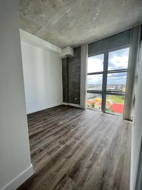 an empty room with a large window and wooden floors