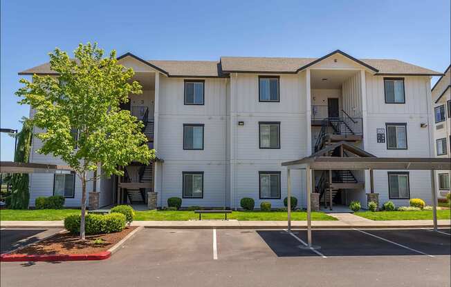 A large white apartment building with a tree in front at Riverplace Apartment Homes, Independence, Oregon
