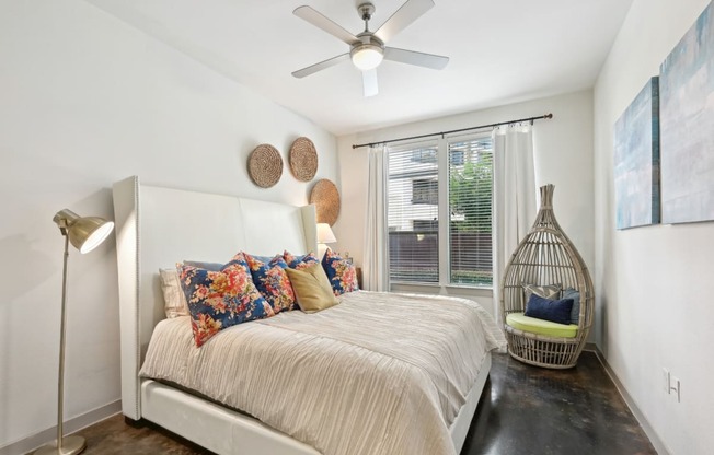 Model bedroom with a bed and a ceiling fan at Harlow River Oaks in Houston, TX