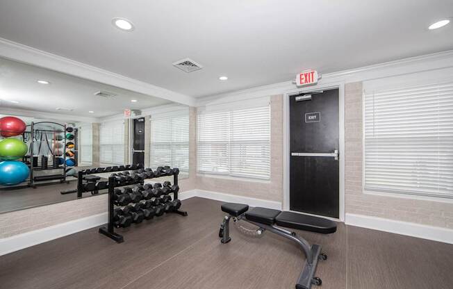 A gym with a variety of equipment including a bench, weights, and a mirror.