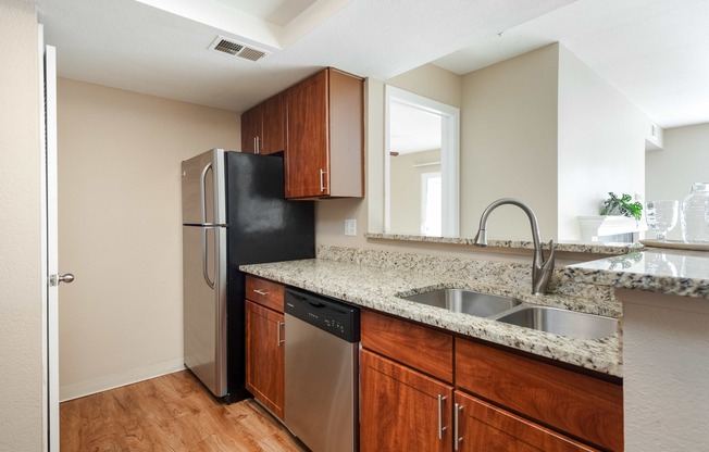 an empty kitchen with a stainless steel refrigerator and sink