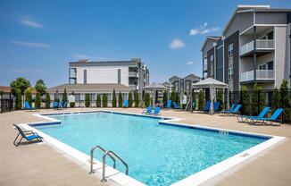 a resort style pool with blue chairs and a building in the background