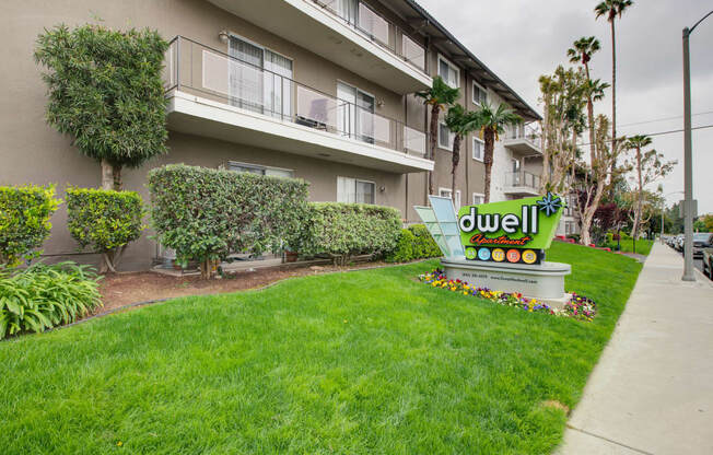 a lawn with a sign in front of an apartment building at Dwell Apartment Homes, Riverside, CA, 92507