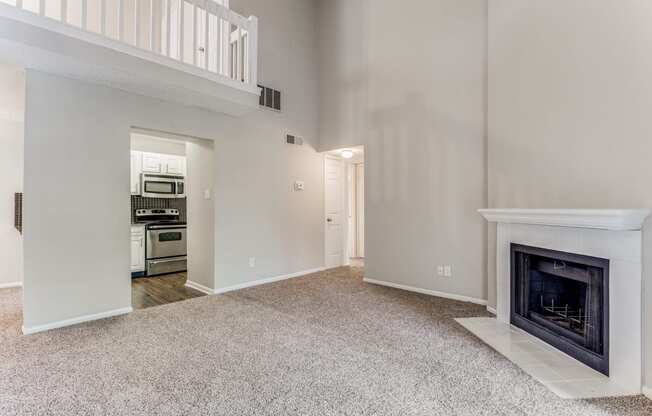 a living room with a fireplace and a kitchen in the background