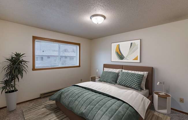 a bedroom with a bed and a potted plant. Fargo, ND West Oak Apartments