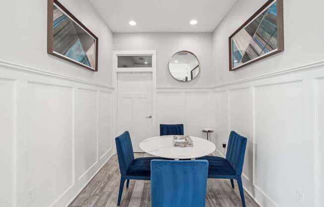 A dining room with a white table and blue chairs.