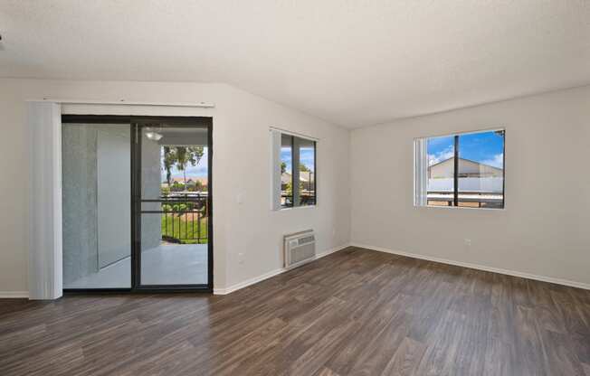 the living room of an apartment with wood flooring and sliding glass doors