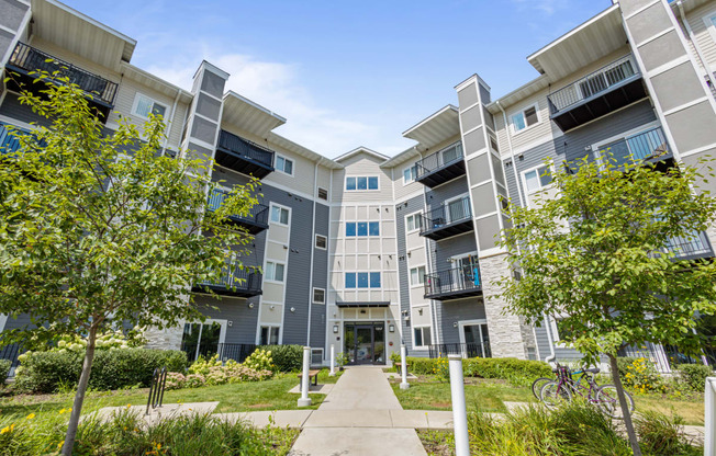 an exterior view of an apartment building with trees and a sidewalk