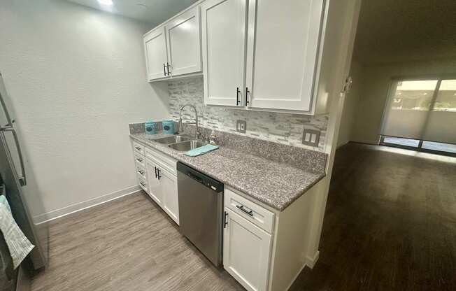 A kitchen with white cabinets and a granite countertop. at Willow Tree Apartments, California, 90505