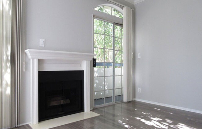 Fireplace with overhanging mantle and large windows with patio access.