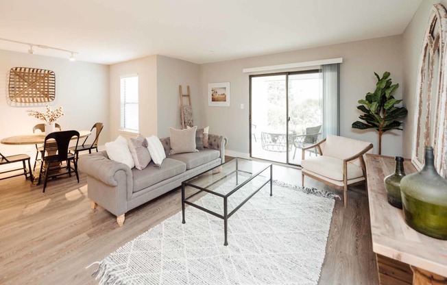 a living room with a gray couch and a glass coffee table in front of a sliding glass